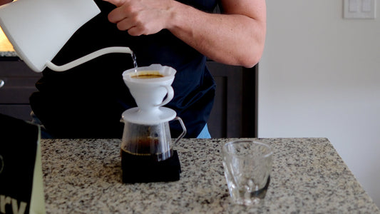 brewing specialty coffee, pouring hot water over freshly ground coffee in a pour-over setup.